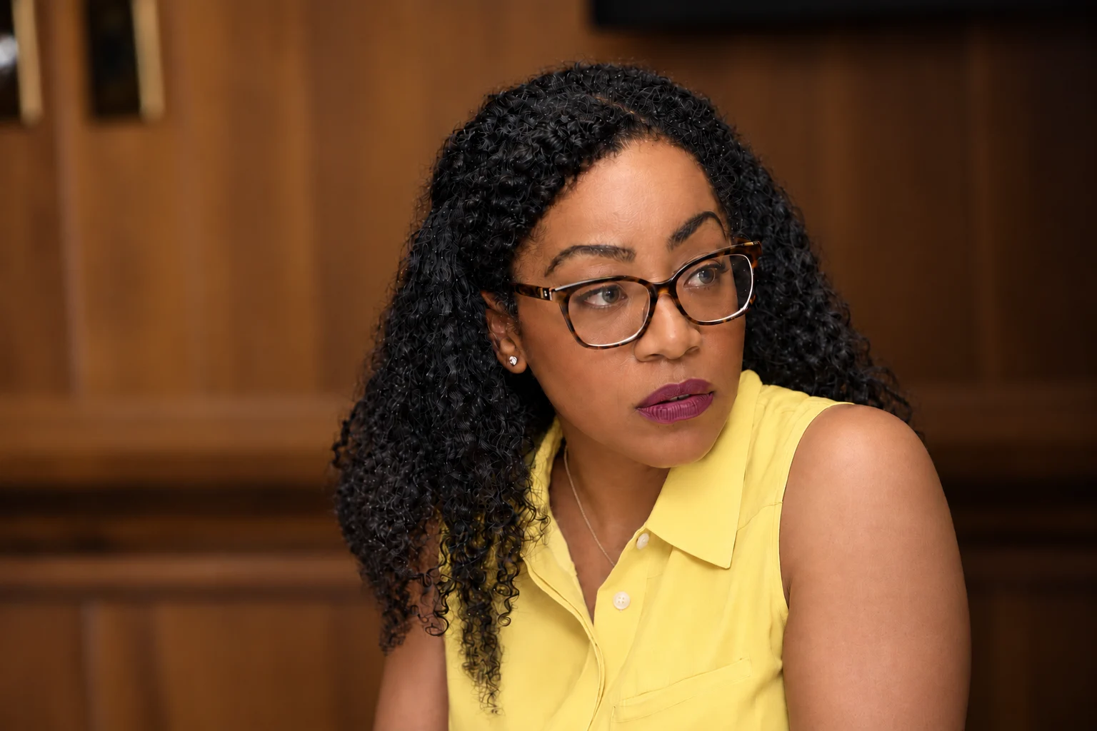 Malia Cohen wearing a yellow blouse and glasses, looking right.